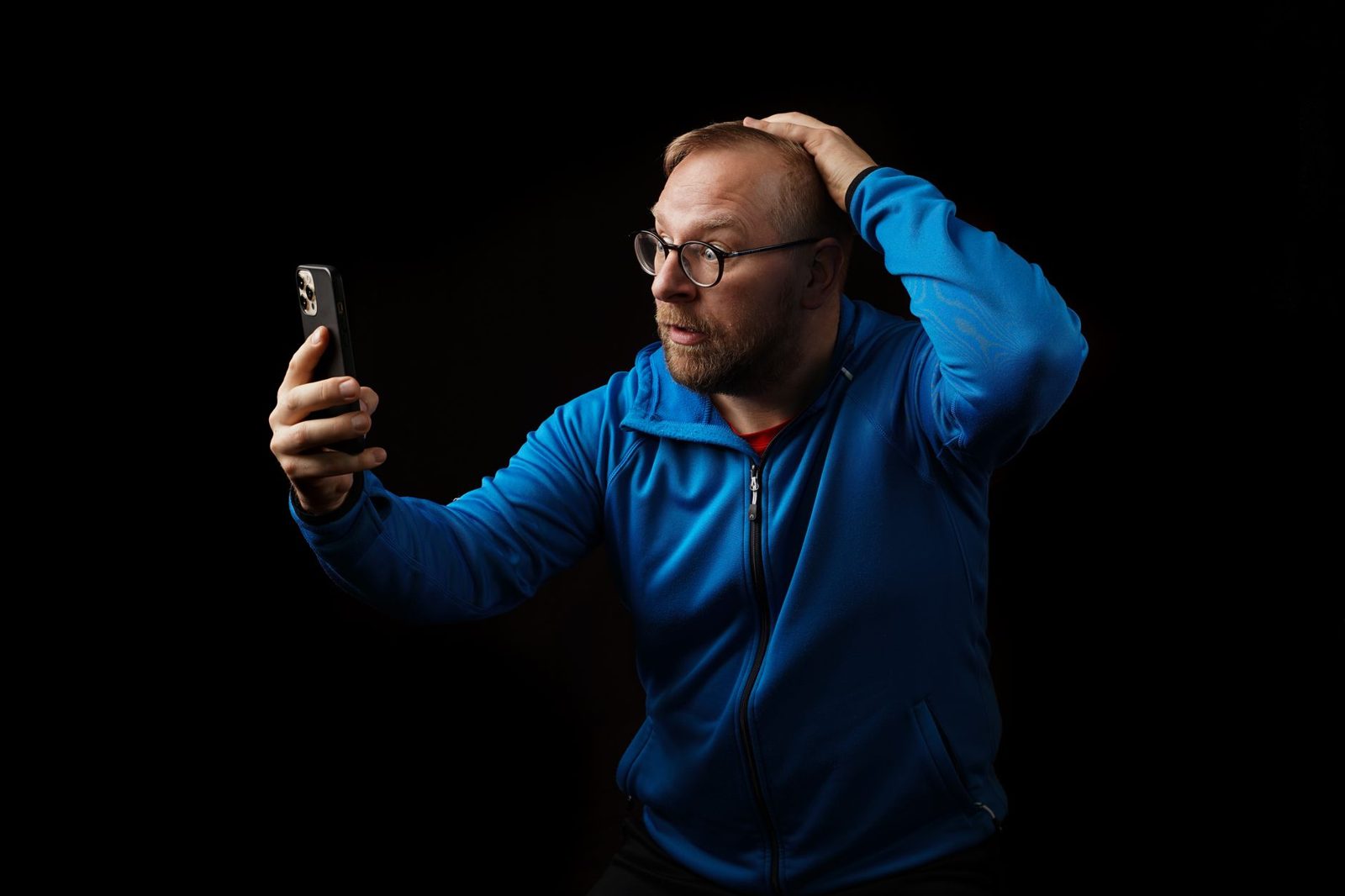Shocked man looking at his phone with his hand on his head